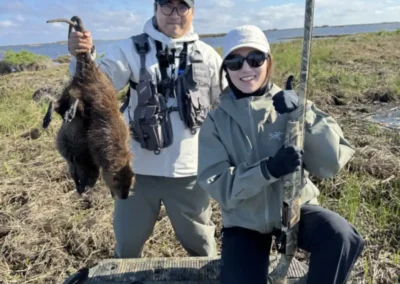 Father and son enjoying a successful Louisiana nutria hunt while posing with harvested nutria on the boat