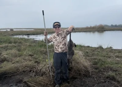 Hunter standing in Louisiana wetlands after a guided nutria hunt with harvested nutria near the boat