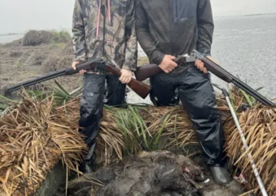 Successful Louisiana nutria hunt with guide and hunter posing beside harvested nutria in coastal marshland