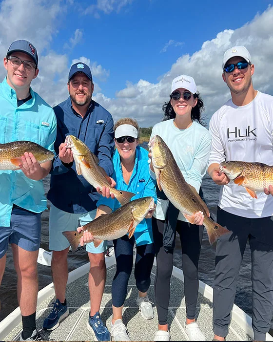 Group of five anglers proudly displaying their catch of fish on a boat, showcasing a successful fishing charter experience in Louisiana.